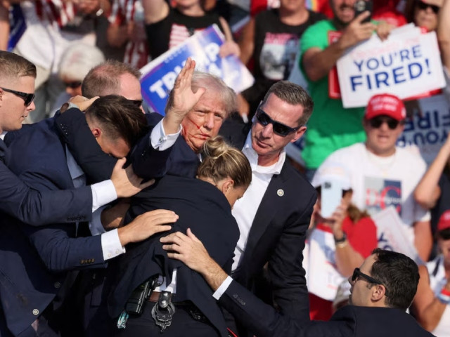 republican presidential candidate and former u s president donald trump gestures with a bloodied face while he is assisted by u s secret service personnel after he was shot in the right ear during a campaign rally at the butler farm show in butler pennsylvania u s july 13 2024 photo reuters